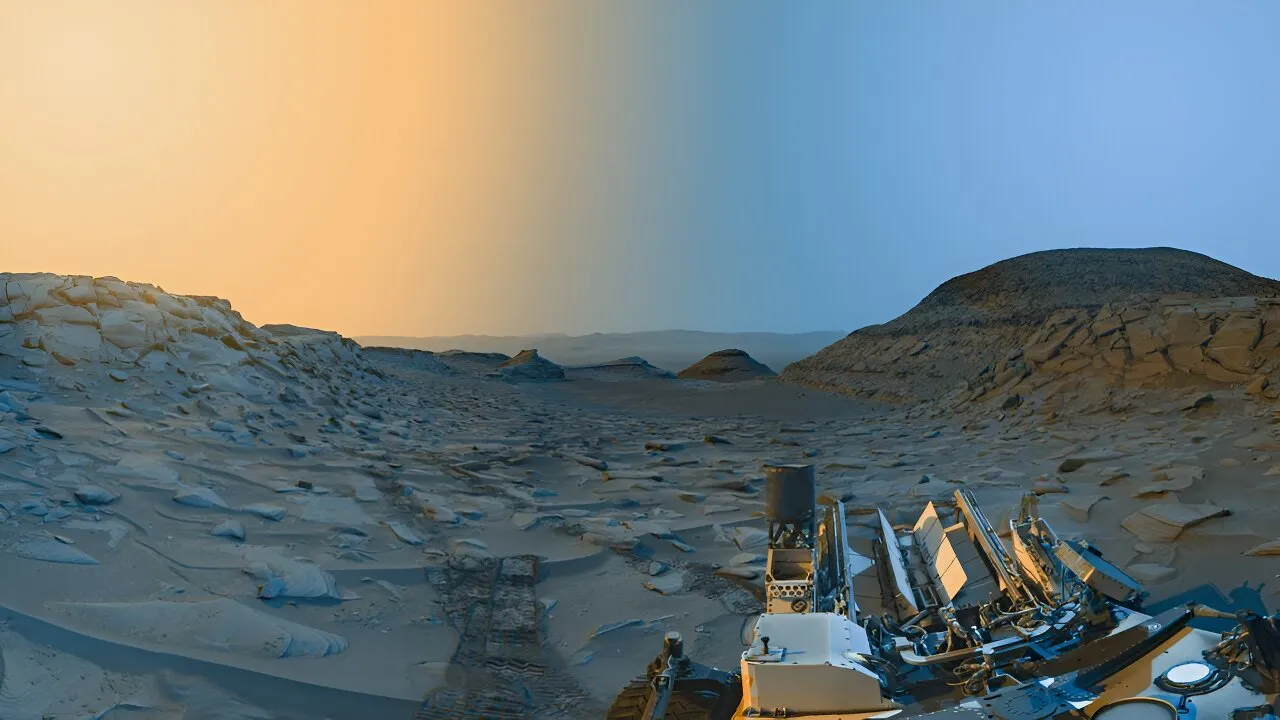 这张全景图是由好奇号于2023年4月8日拍摄的火星盖尔陨石坑标记带谷(Marker Band Valley)的两张照片合并而成,分别是在当地时间的上午和下午。原始图像是黑白拍摄的,然后进行了着色,右边部分(蓝色天空)代表上午的场景,左边部分(黄色天空)代表下午的场景。This panorama was merged from two images of “Marker Band Valley” in Mars’s Gale crater taken by Curiosity on 8 April 2023, one in the morning and one in the afternoon local time. The original images were taken in black and white and then colorized, with the right portion (under blue sky) representing the scene in the morning and the left portion (under yellow sky) representing the afternoon. Credit: NASA/JPL-Caltech